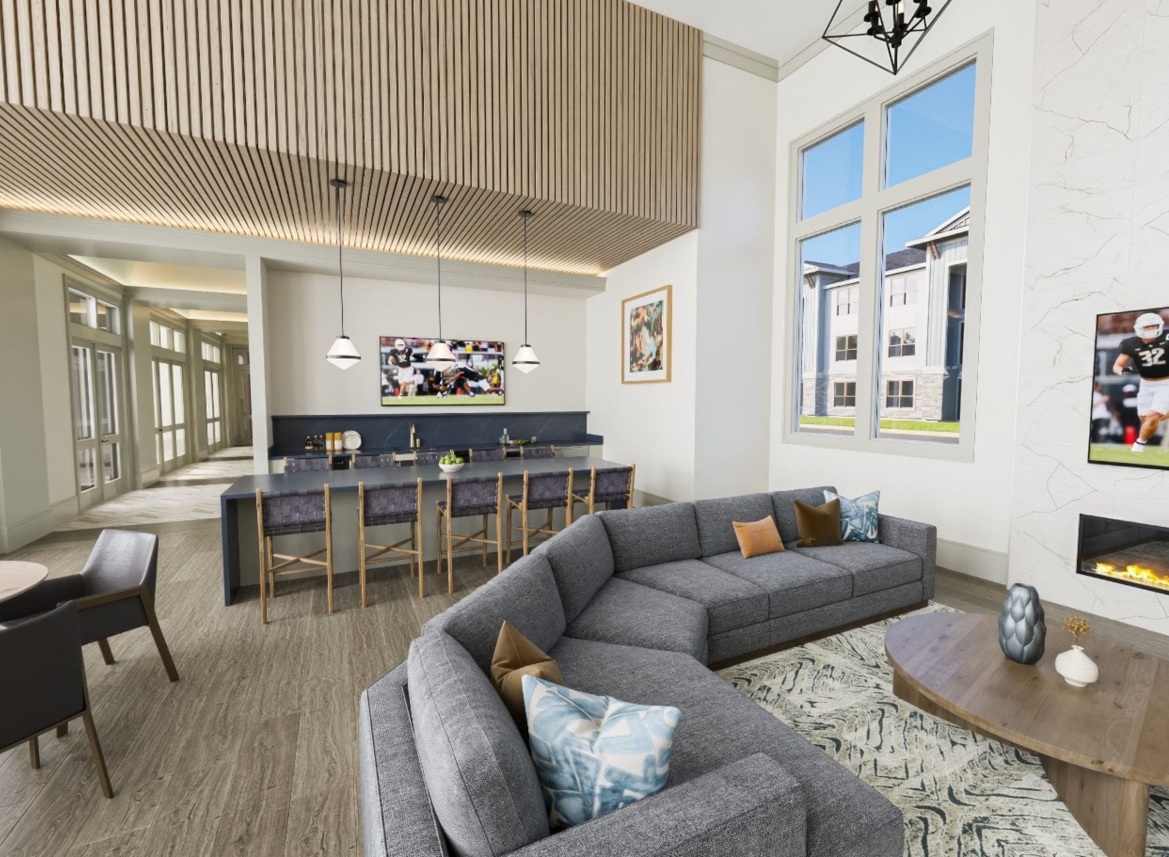 Modern lounge with gray sectional sofa, TV, fireplace, dining area, and large windows letting in natural light.