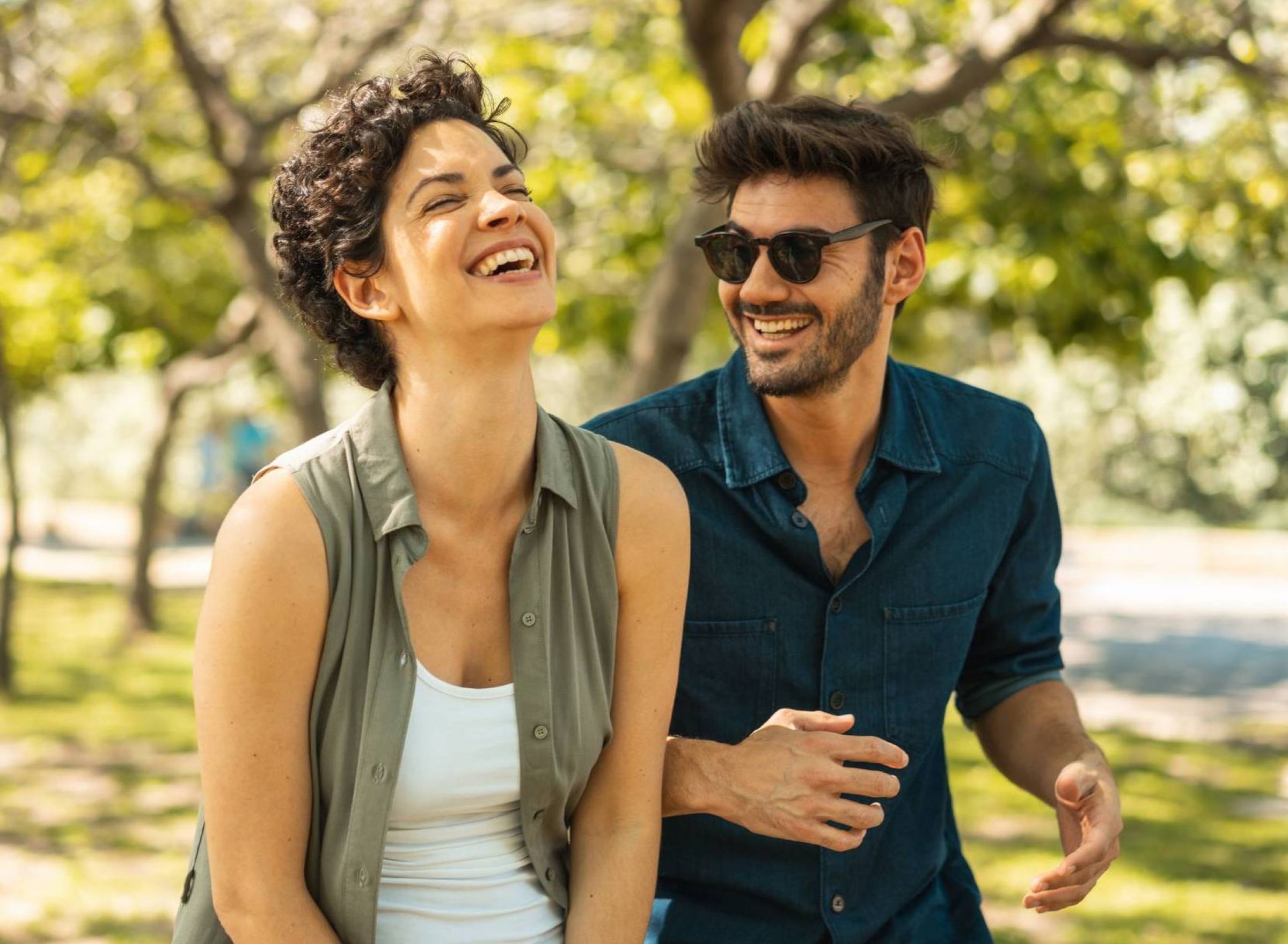 Monteverde luxury apartments in San Antonio, TX with a young happy couple laughing while walking in a beautiful green park